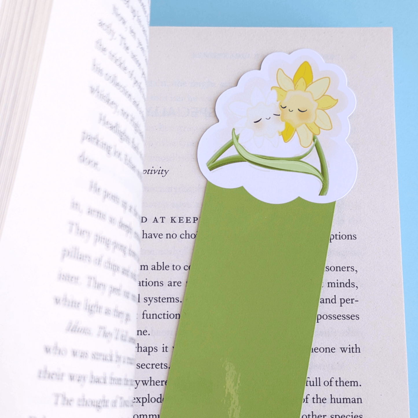 A close-up detail shot showing the top two-thirds of the Meadow Green Daffodil Hug Szn bookmark in an open copy of Remarkably Bright Creatures. The image captures the gloss light tint across the high-res photo media, showcasing the water-resistant material of the die-cut bookmark, emphasizing the vibrant green aesthetic for book annotating.