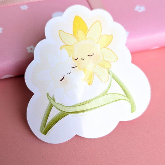 Ateu Studio Daffodil Hug SZN gloss vinyl sticker showing a reflective sheen in natural afternoon sunlight. This close-up highlights the water-resistant finish and vibrant spring colors, ideal for personalizing water bottles and tech.