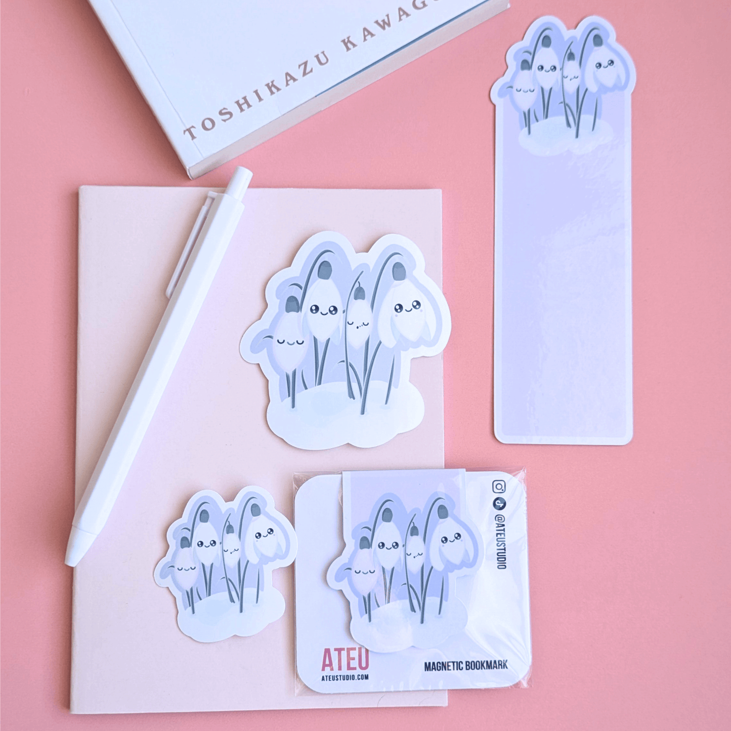 An airy, minimalist reading nook scene featuring Ateu Studio Sleepy Snowdrop 'Dawn' stationery styled with Toshikazu Kawaguchi’s 'Before the Coffee Gets Cold.' The lavender-blue and Snowdrop White stickers, gloss bookmark, and magnetic bookmark are arranged on a pink pocket notebook. This bright, breathable rose-pink composition captures a cozy moment of aesthetic joy, ideal for book annotating and Kindle decorating.