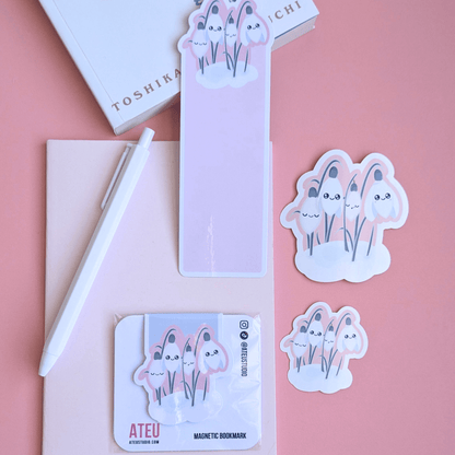 An airy reading nook scene featuring an Ateu Studio Sleepy Snowdrop Icy Venusian Pink stationery set styled with Toshikazu Kawaguchi’s 'Before the Coffee Gets Cold.' The Snowdrop White characters with a cozy soft-glow effect are arranged on a pink pocket notebook, capturing a bright, breathable moment of aesthetic joy for book annotating.