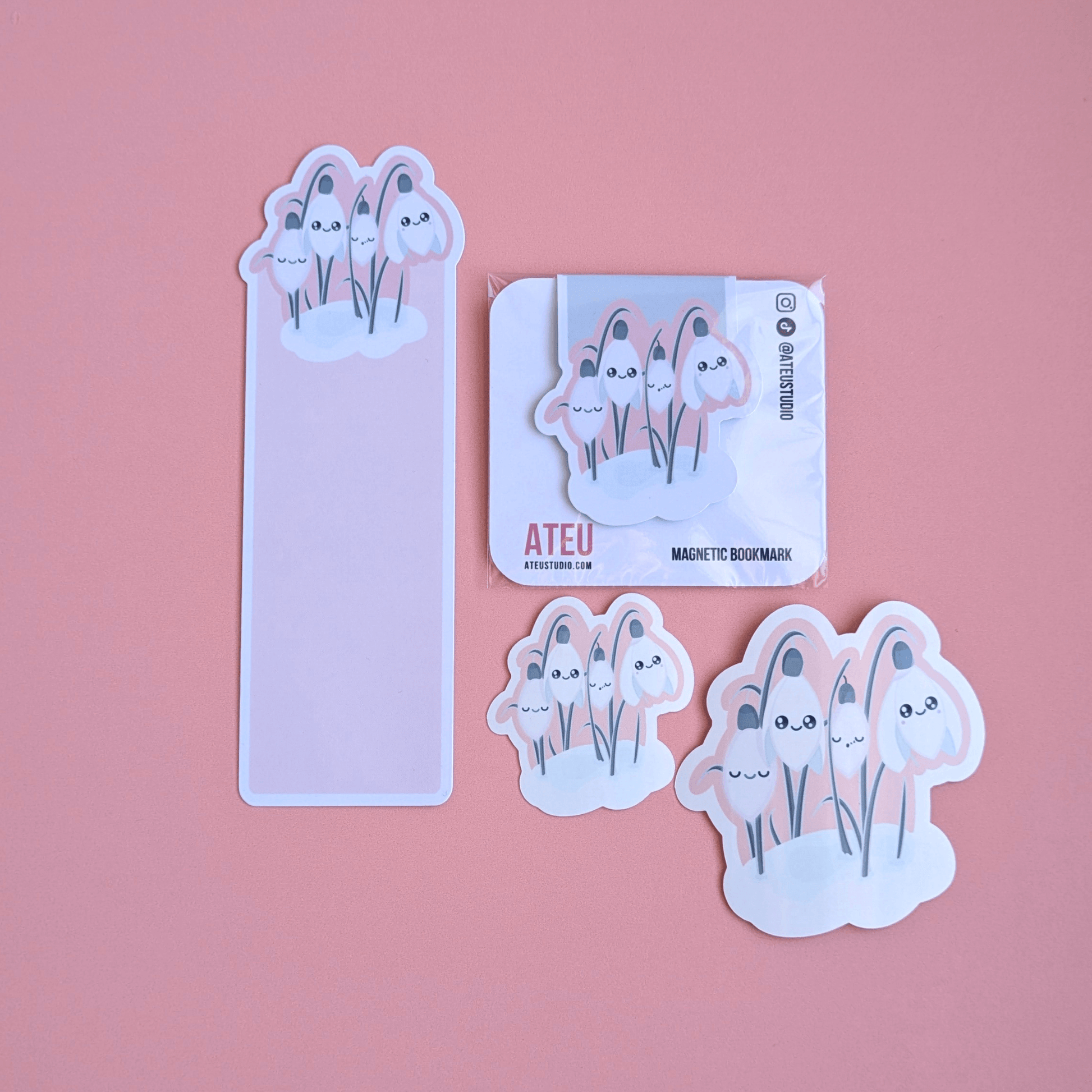 Ateu Studio Sleepy Snowdrop 'Icy Venusian' Pink Kawaii stationery gift set featuring Snowdrop White characters and a cozy soft-glow effect. The aerial view showcases the die-cut bookmark, magnetic bookmark, and two gloss vinyl stickers on a rose-pink background, highlighting the high-shine finish for Kindle decorating and gifting.