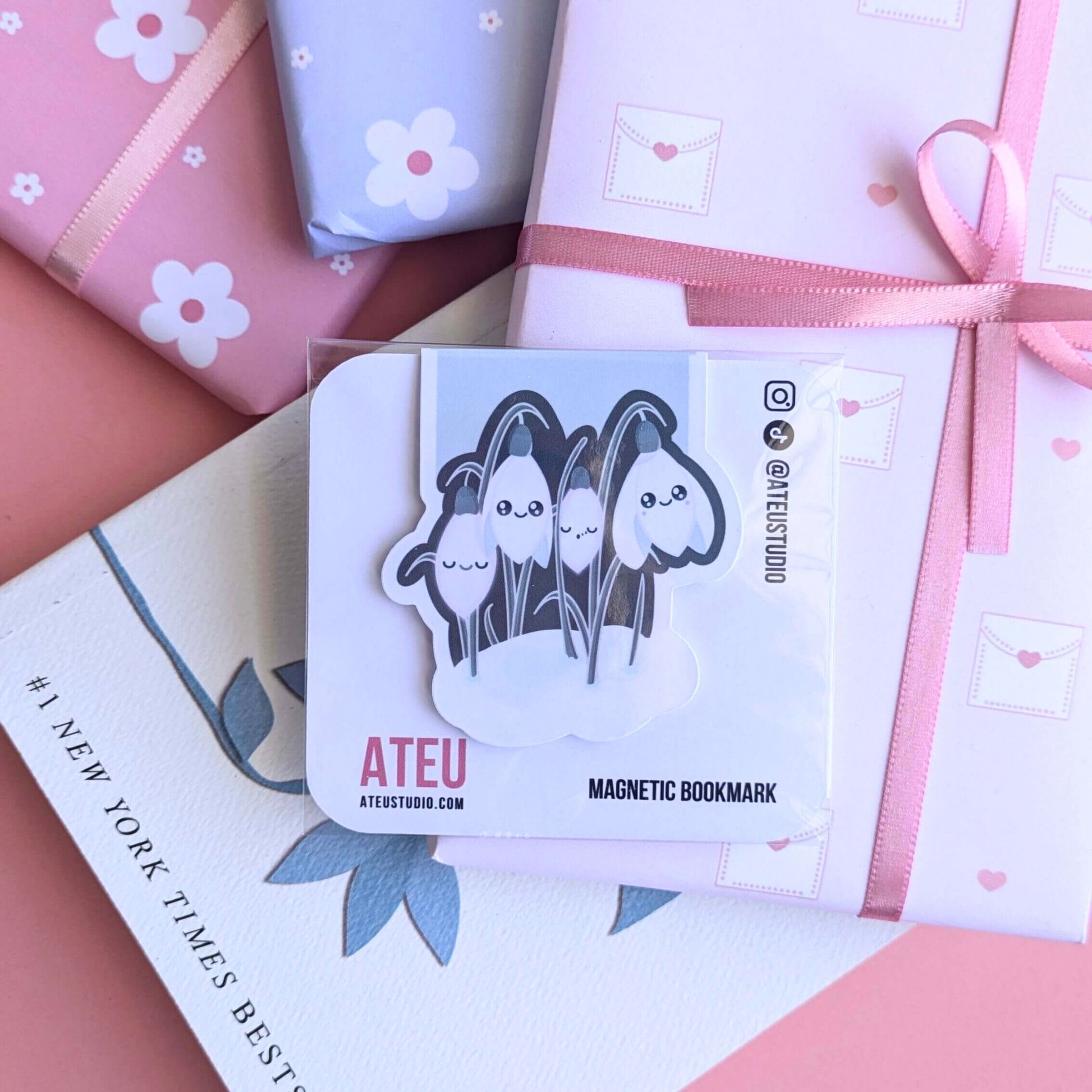 A close-up view of the Ateu Studio Kawaii Sleepy Snowdrop 'Winter’s Edge' Teal magnetic bookmark on its branded backing card. The retail packaging shows the Kawaii character art clearly, with a soft light reflection. This shot highlights the premium presentation designed for aesthetic planning and book-safe decorating - an essential, book safe gift add-on for curated literary bundles.