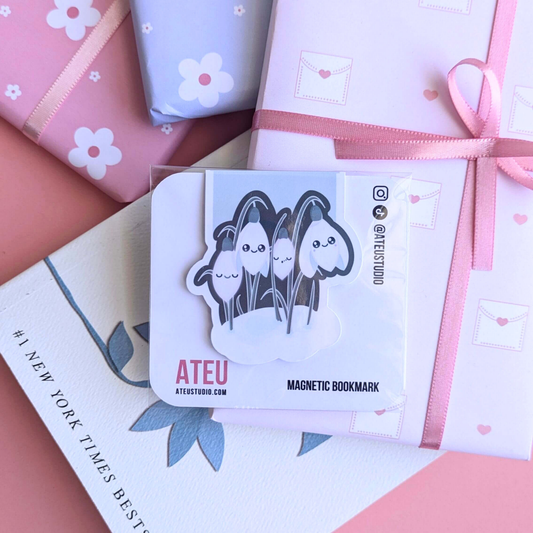 A close-up view of the Ateu Studio Kawaii Sleepy Snowdrop 'Winter’s Edge' Teal magnetic bookmark on its branded backing card. The retail packaging shows the Kawaii character art clearly, with a soft light reflection. This shot highlights the premium presentation designed for aesthetic planning and book-safe decorating - an essential, book safe gift add-on for curated literary bundles.