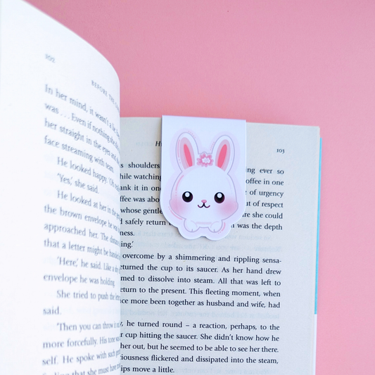 Aerial view of the Marshmallow Blush Bunny magnetic bookmark in pink and white, clipped to a page of Before the Coffee Gets Cold by Toshikazu Kawaguchi. This Ateu Studio character adds a pop of joy to a cozy reading environment, perfect for romanticized book annotating and aesthetic life-building.