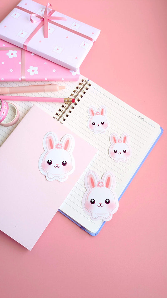 Ateu Studio Marshmallow Blush Bunny gloss vinyl stickers in pink and white, styled in a flat lay with lavender spiral notebooks, daisy-patterned gift wrap, and pink washi tape. This vibrant, color-obsessed stationery scene highlights how to use kawaii stickers for journaling and gift-giving.