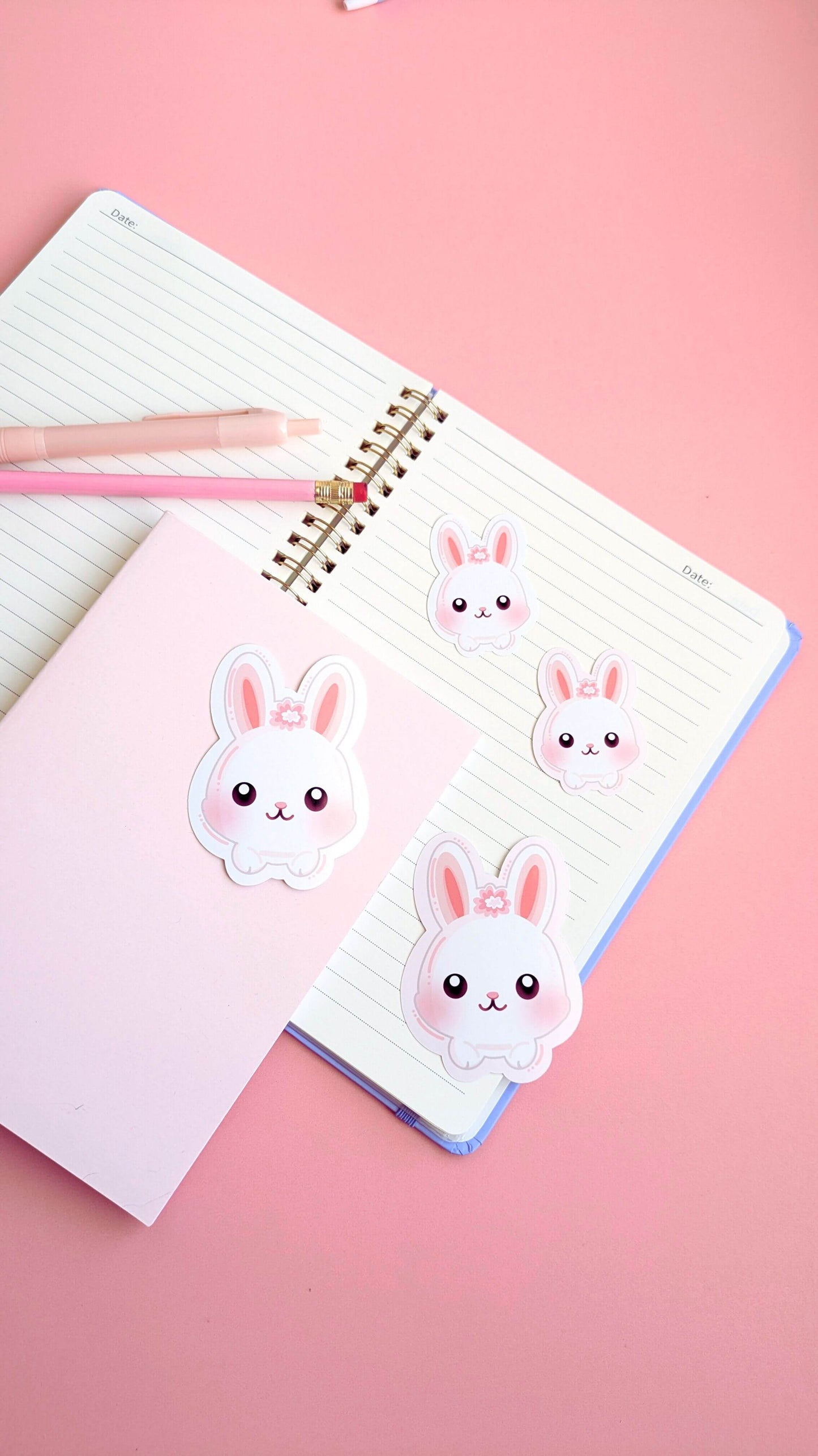 Ateu Studio Marshmallow Blush Bunny stickers arranged on an open lavender spiral notebook. This clean, minimalist flat lay highlights the color harmony between the pink stickers and pastel stationery, perfect for simple journaling inspiration.