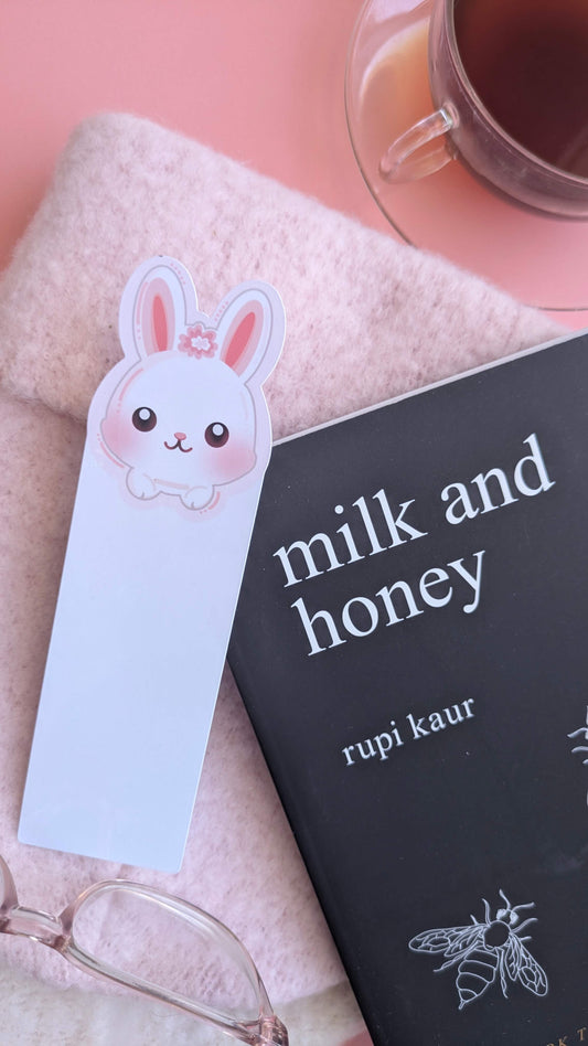 Ateu Studio Marshmallow Blush Bunny bookmark in Snowball White, styled with a copy of Milk and Honey by Rupi Kaur, a cup of English Rose black tea, and a soft pink winter hat. This winter-themed reading nook scene captures a mindful, cozy moment of rest and aesthetic joy.