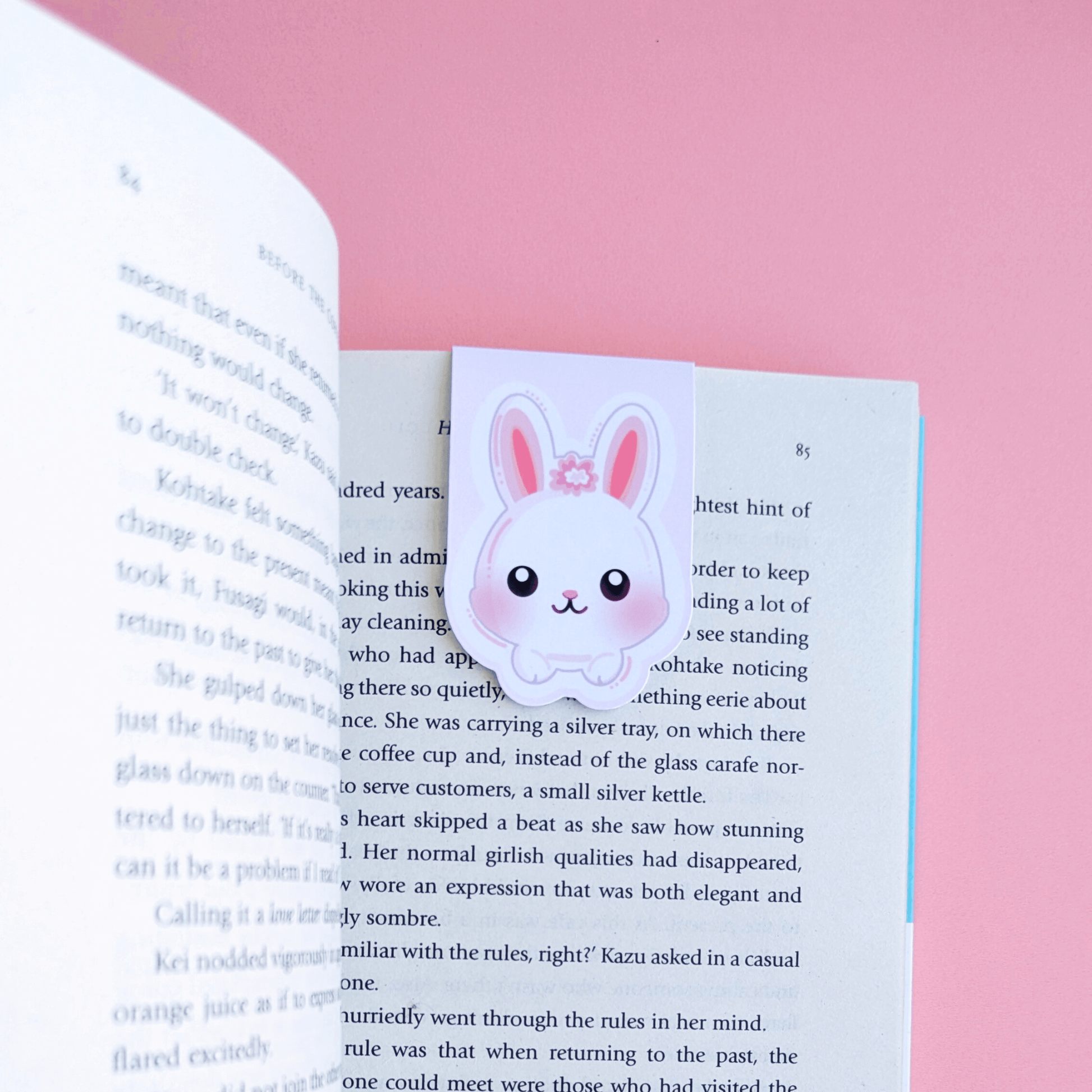 Marshmallow Blush Bunny magnetic bookmark in Snowball White with pink accents, clipped to a physical copy of Before the Coffee Gets Cold by Toshikazu Kawaguchi. A cozy reading accessory by Ateu Studio, perfect for book annotating and romanticizing your reading routine.