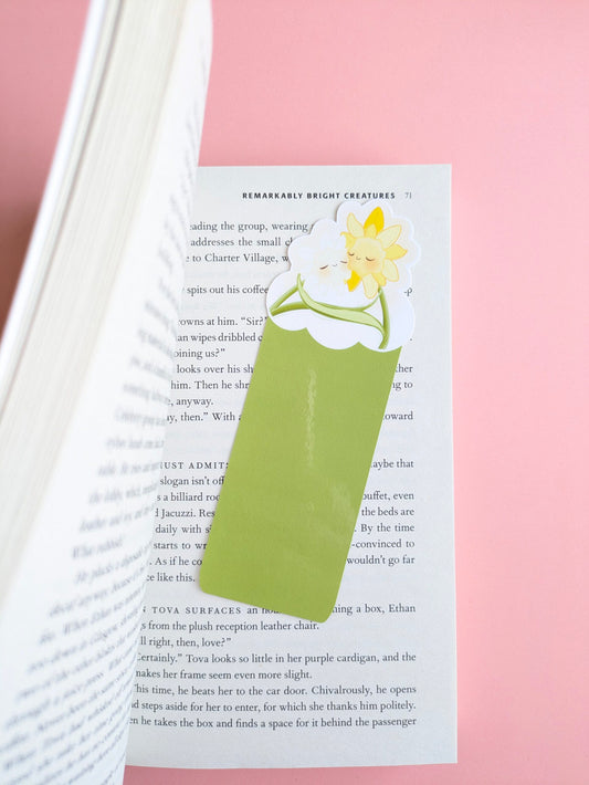 The bookmark is angled toward the top right , with the left-hand pages showing depth as if the book was just opened for a reading ritual. A soft gloss light tint is visible on the bookmark base highlighting the protective heat-laminate finish.