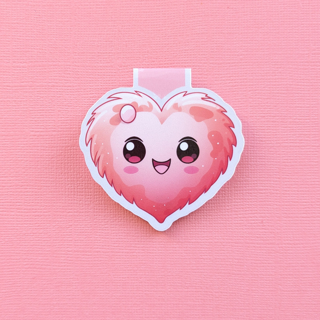 Close-up of a My Fuzzy Valentine magnetic bookmark on a pink textured card background, captured in soft natural light to highlight the bookmark's durable texture and secure magnetic grip.