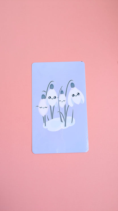 An aerial view of the 'Sleepy Snowdrops Dawn Lavender Blue Kindle Paperwhite Insert' resting on a soft pink background. The high-res photo media features the original kawaii characters in a morning sky palette with a clear gloss finish.