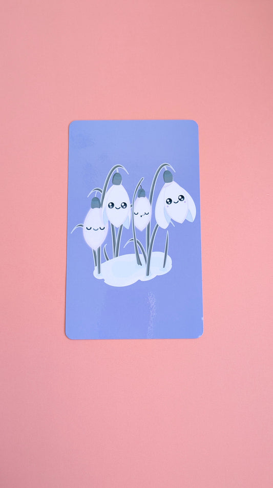 An aerial view of the 'Midnight Mist' lavender-blue Kindle Paperwhite insert resting on a soft pink background. The high-res photo media reveals original kawaii Sleepy Snowdrops characters against a winter sky, highlighting the high-gloss finish and monochrome aesthetic for Kindle decorating.
